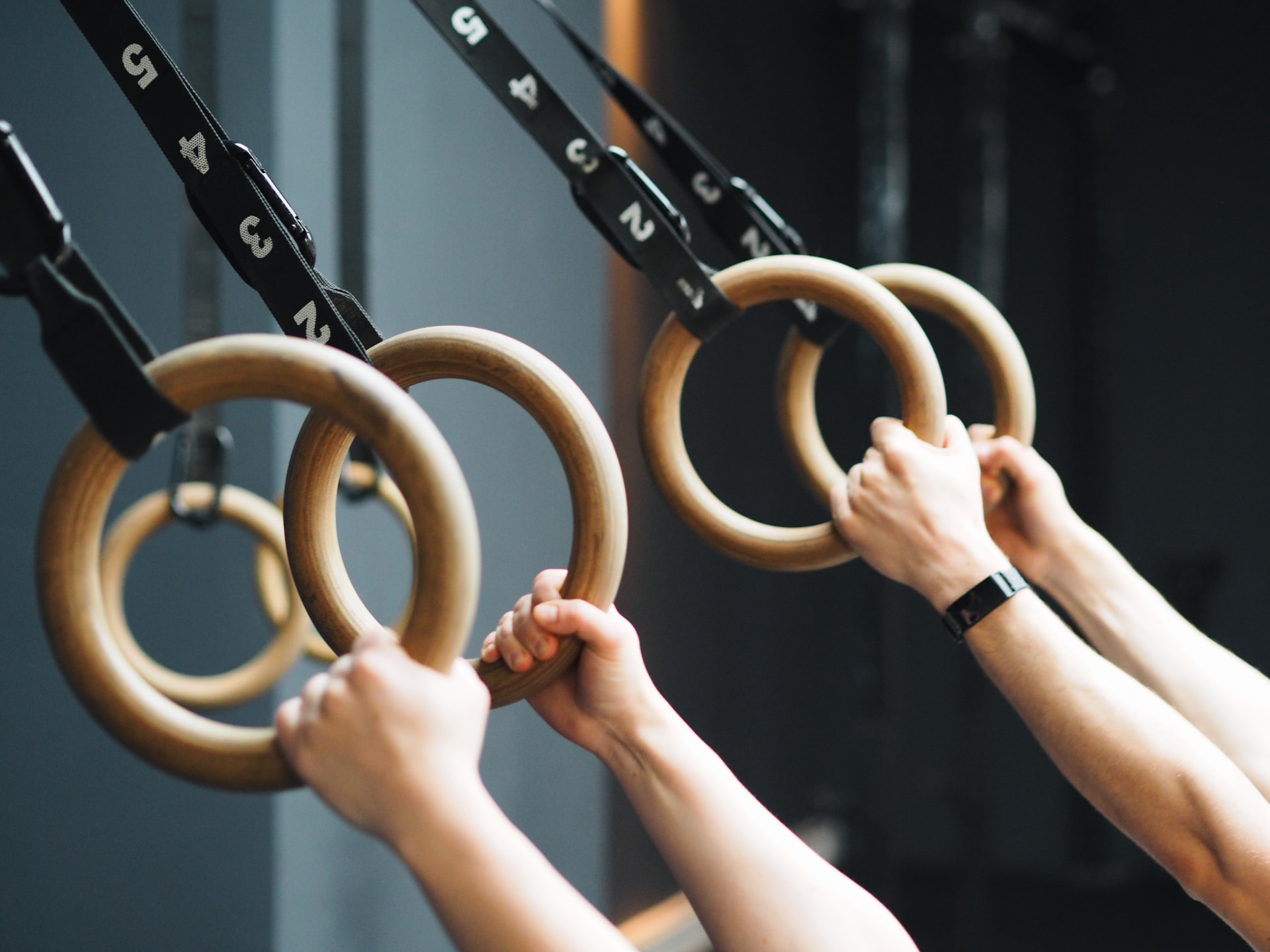 Hands gripping wooden gymnastic rings during a session at Studio 58